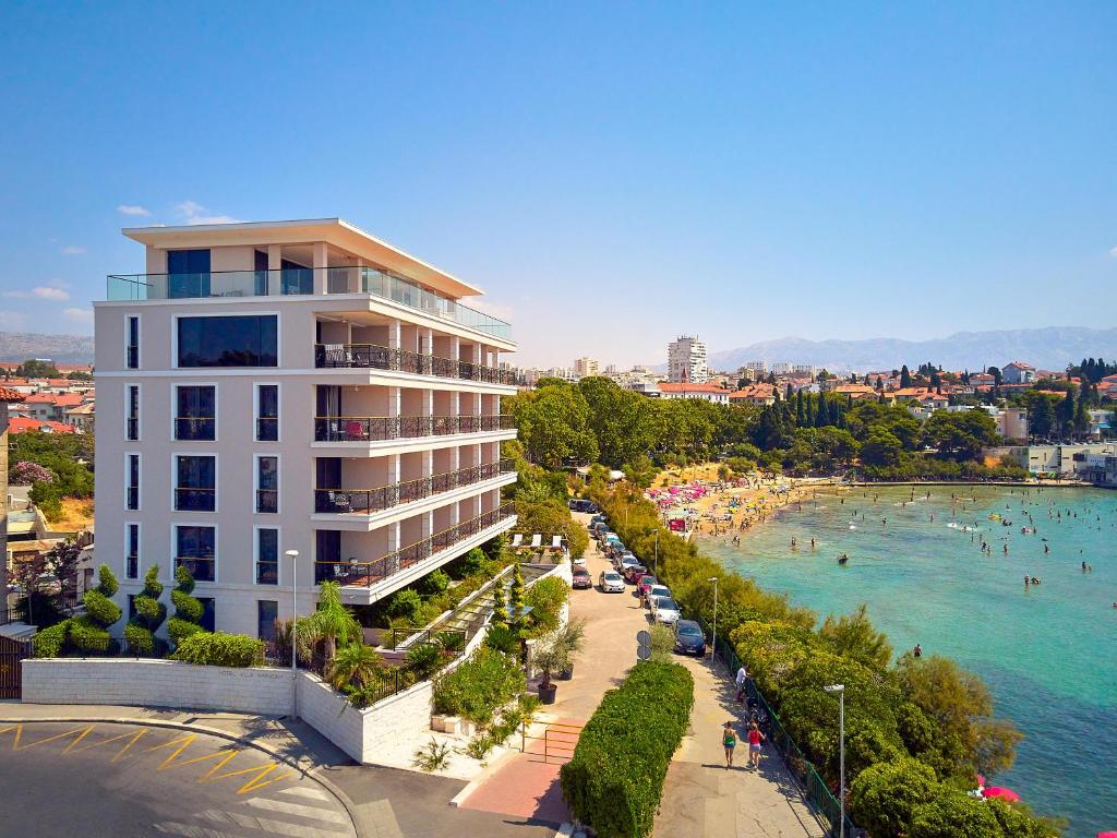 a building next to a beach with people in the water at Hotel Villa Harmony in Split