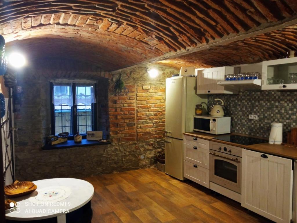 a kitchen with white appliances and a brick wall at Chalupa u Brčáků in Ktiš