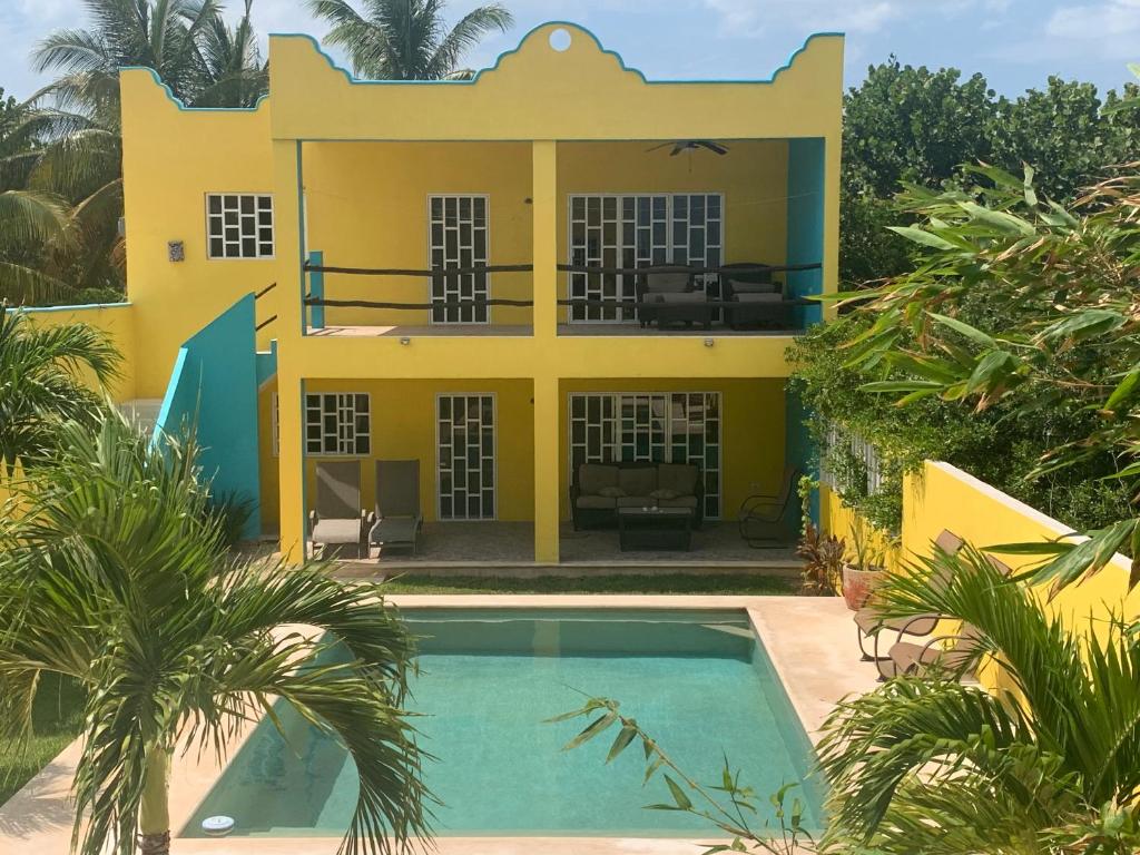 een geel huis met een zwembad ervoor bij Arenas Del Mar Condos in Chelem