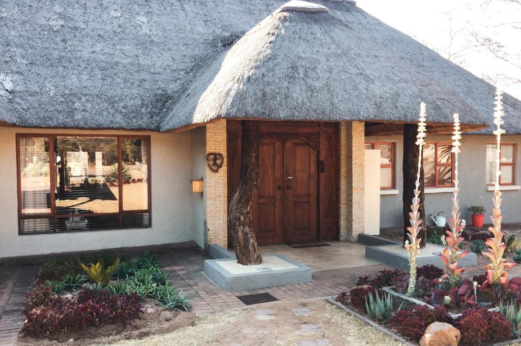 a house with a thatched roof with a door at Waterberg INN in Modimolle