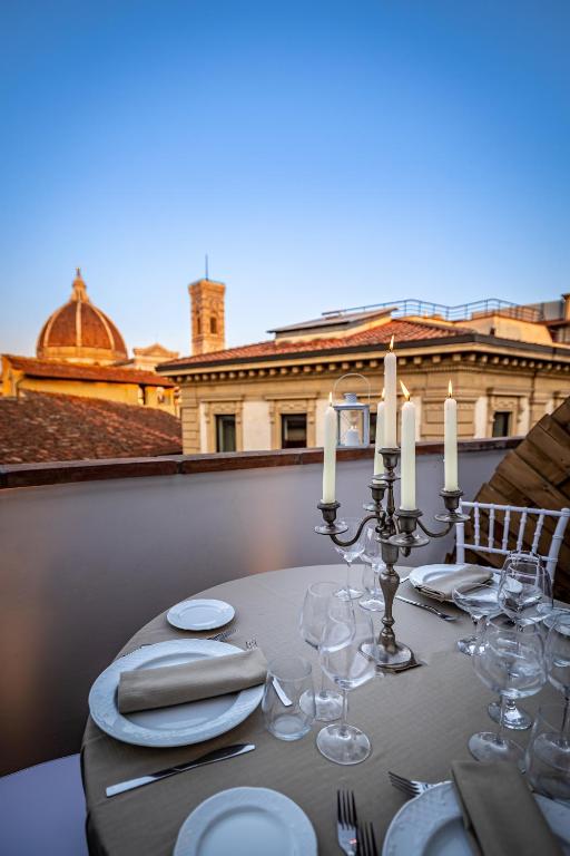 a table with white plates and candles on a balcony at Palazzo dei Conti Residenza d'Epoca in Florence