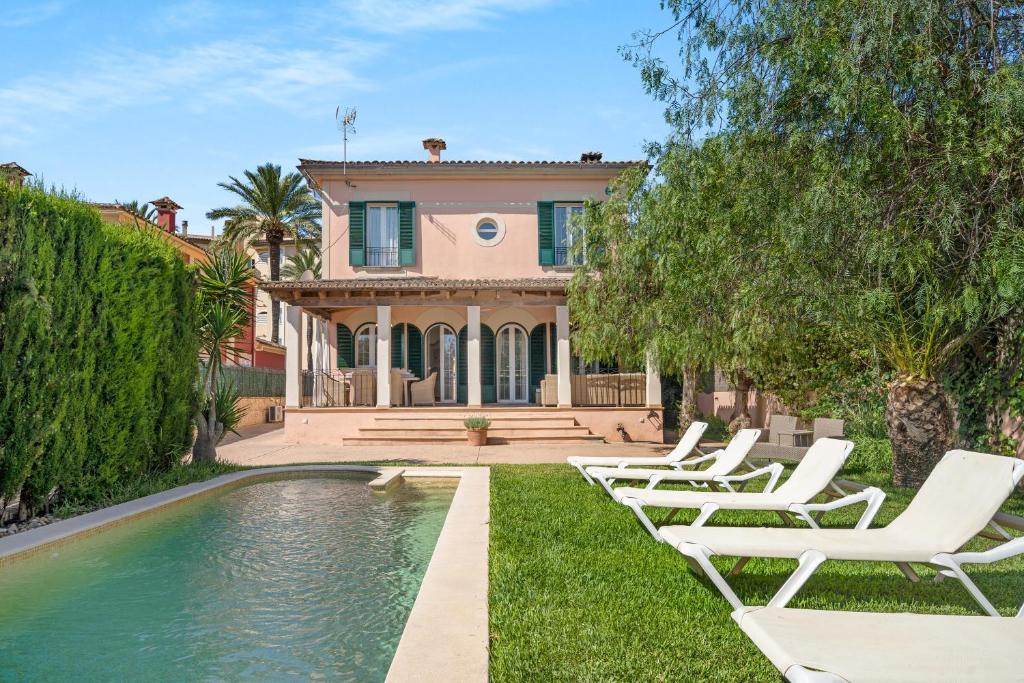 a house with a swimming pool and lounge chairs at Villa Playa Felostal in Palma de Mallorca