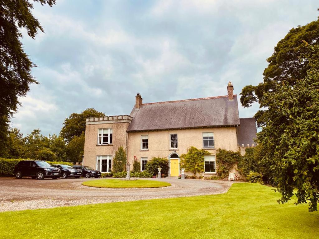 a large house with cars parked in the driveway at Templemacateer in Westmeath