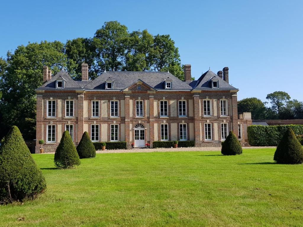 un antico palazzo con un grande prato e alberi di Château de Cleuville a Cleuville