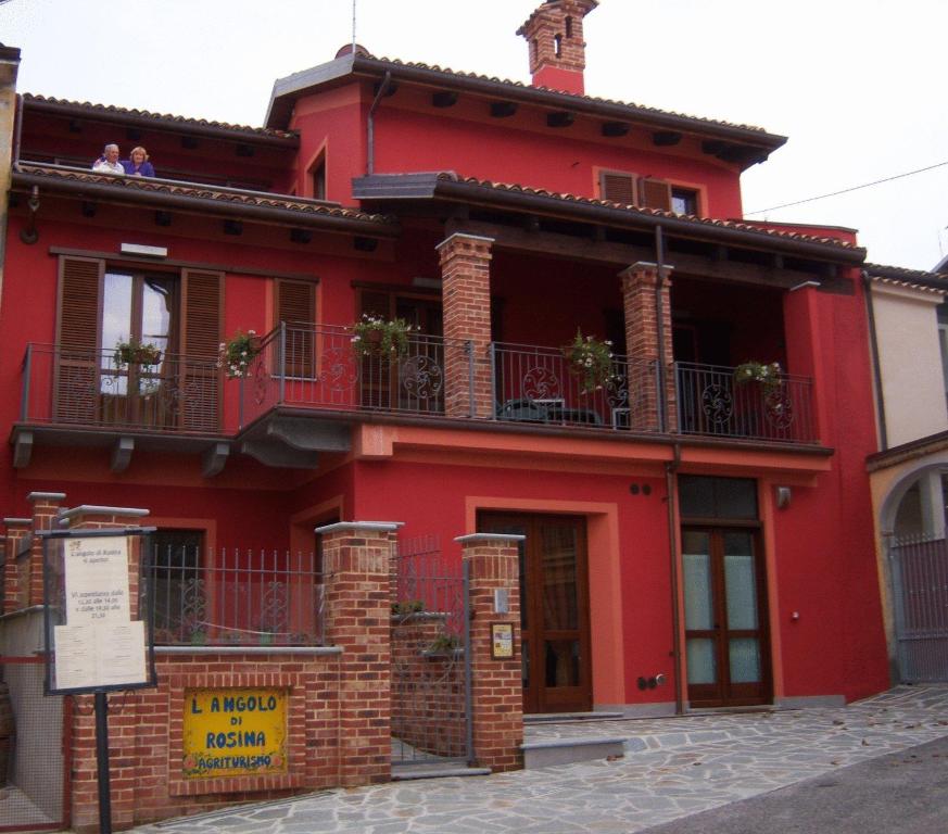 a red house with a balcony on a street at L'Angolo di Rosina in Novello