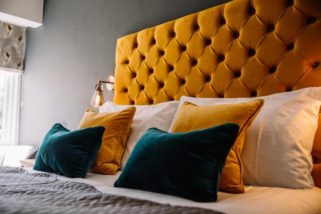 1 dormitorio con 1 cama grande con almohadas amarillas y verdes en Crooklands Hotel, en Crooklands
