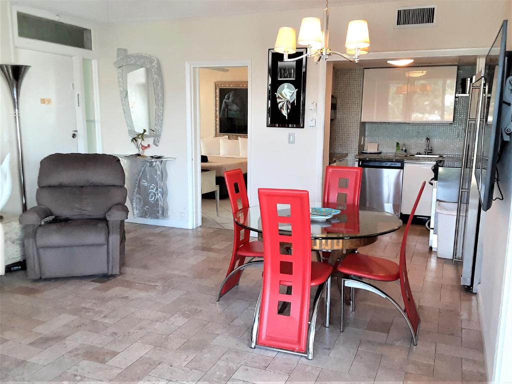 a kitchen and dining room with a table and red chairs at Manhattan Tower Apartment Hotel in Fort Lauderdale