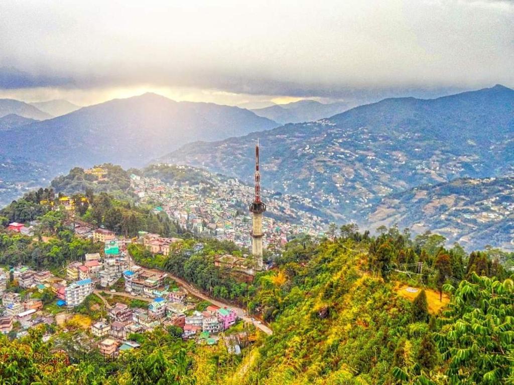 a view of a city with a radio tower on a hill at Aura Homes in Gangtok