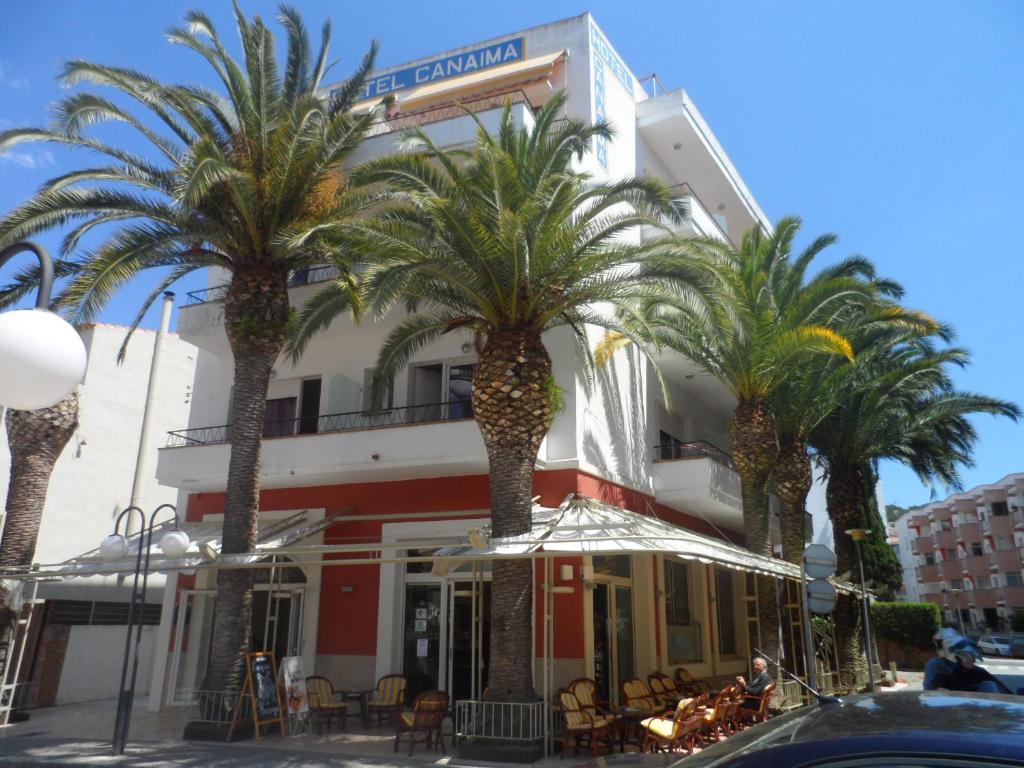 a group of palm trees in front of a building at Hotel Canaima in Tossa de Mar