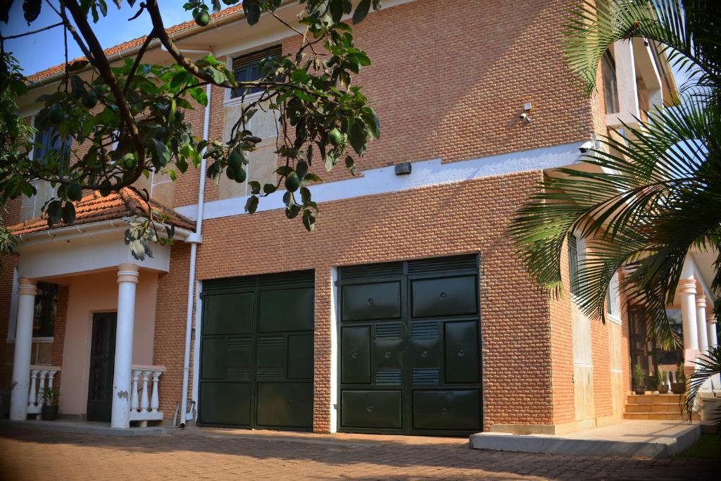 a brick building with green garage doors on it at Nile Estates Villa Kiwatule in Kampala