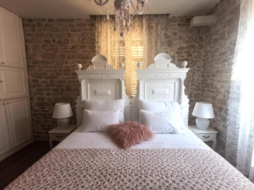 ein Schlafzimmer mit einem weißen Bett und einem pelzigen Kissen darauf in der Unterkunft L&L Rooms Royal in Šibenik