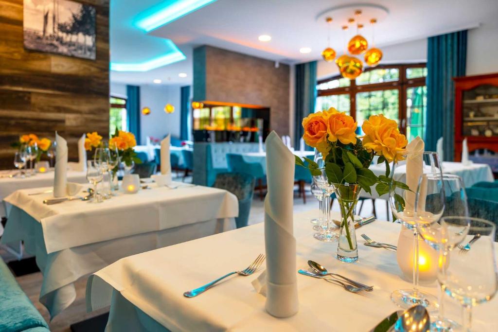 a dining room with white tables with yellow flowers on them at Hotel Blinkfüer in Dierhagen