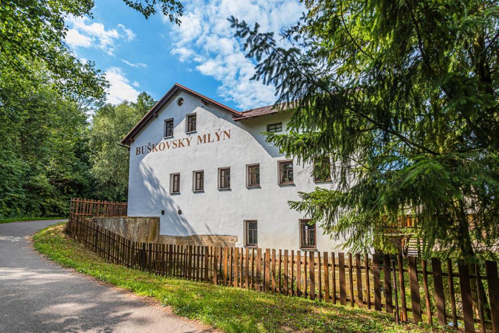 um edifício branco com uma cerca de madeira ao lado de uma estrada em Buškovský mlýn 1580 em Dolní Bousov