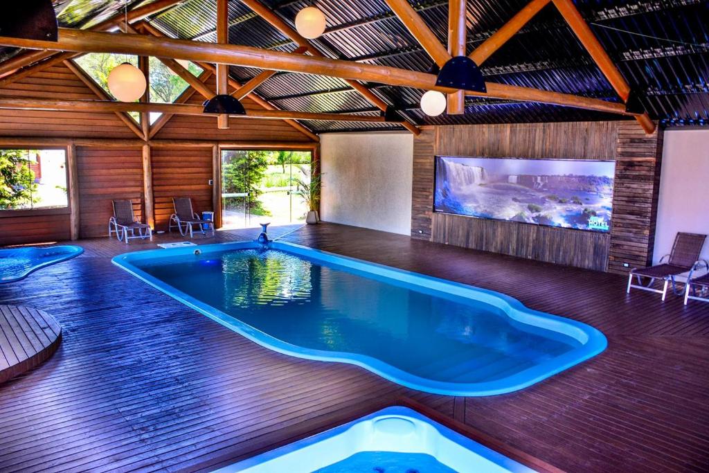 a large swimming pool in a room with a tv at Eco Hotel Bouganville in São José dos Pinhais