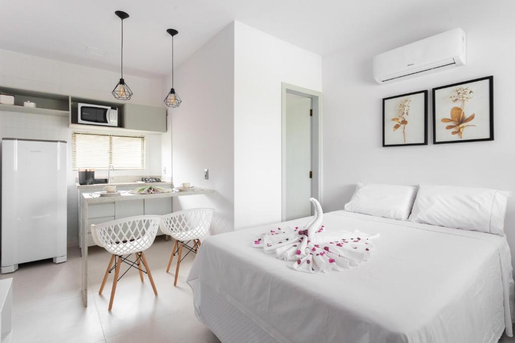 ein weißes Schlafzimmer mit einem weißen Bett und einer Küche in der Unterkunft Quinta do Mar Flats Porto de Galinhas in Porto De Galinhas