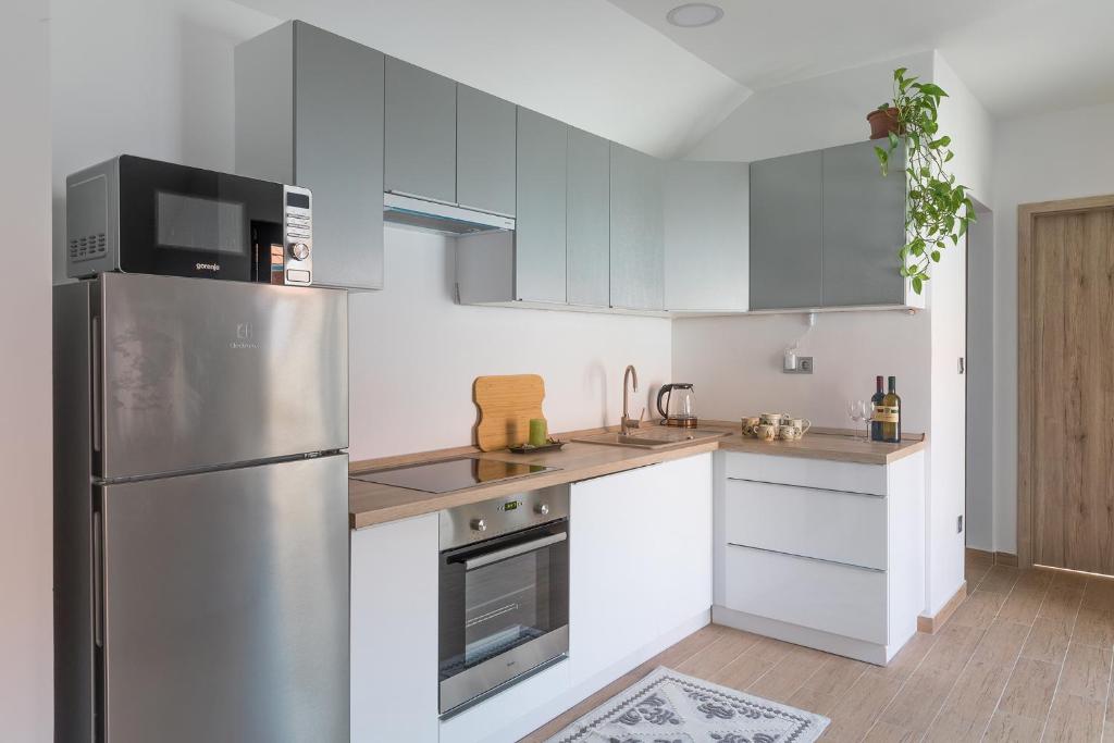 a kitchen with white cabinets and a stainless steel refrigerator at Stay Veszprèm, modern city center flat in Veszprém