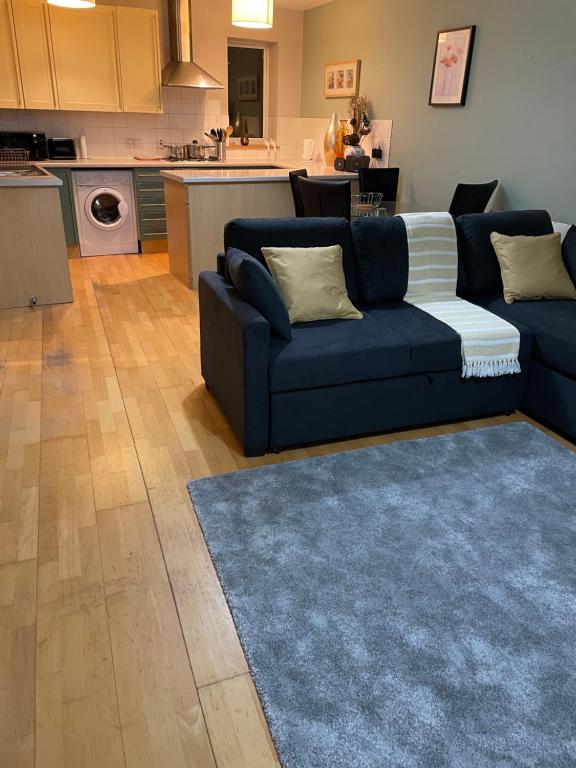 GREENWICH CENTRE NKY APARTMENT في لندن: غرفة معيشة مع أريكة زرقاء ومطبخ