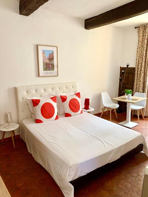une chambre avec un lit avec des oreillers rouges et blancs dans l'établissement le 1835, studio rouge-Corail, à Moustiers-Sainte-Marie