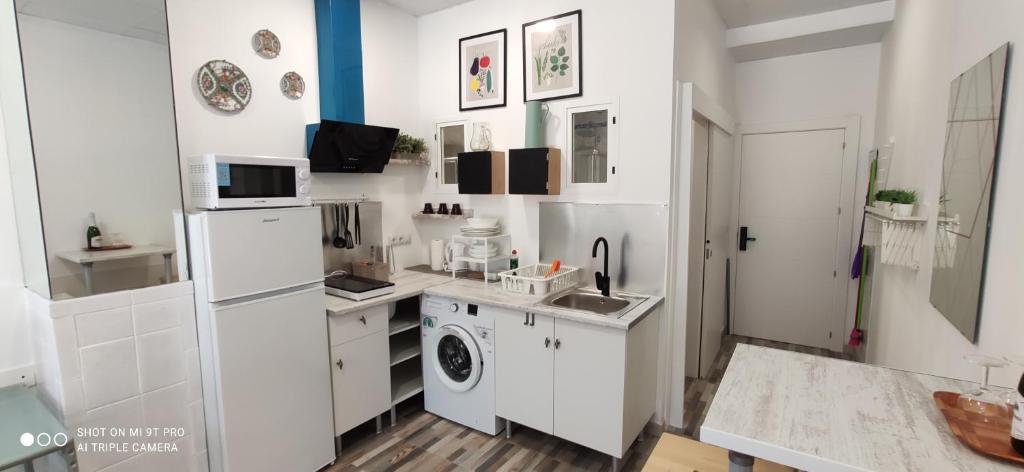 a kitchen with white cabinets and a washer and dryer at Huelintown in Málaga