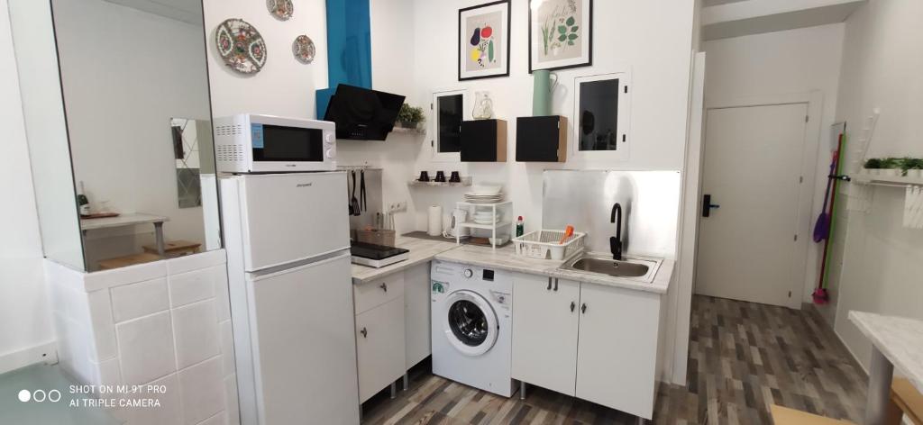 a white kitchen with a refrigerator and a washing machine at Huelintown in Málaga