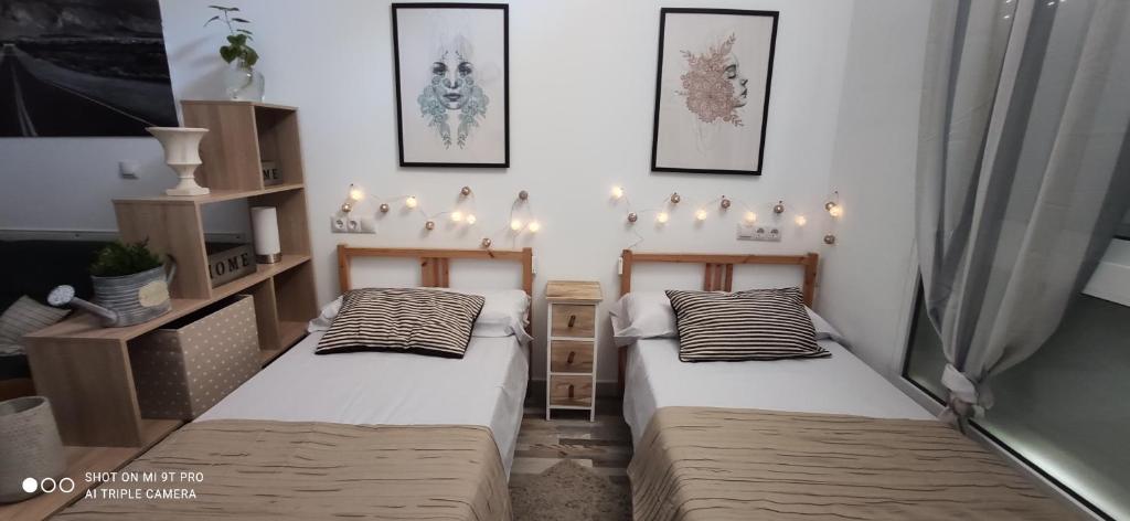 two beds in a room with lights on the wall at Huelintown in Málaga
