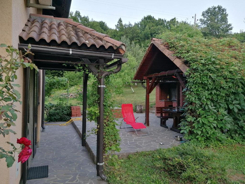 a patio with a gazebo and a red chair at Kuća za odmor Silver pine in Ogulin