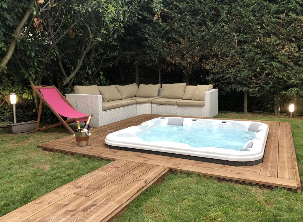un bain à remous sur une terrasse en bois avec un canapé dans l'établissement La maison penchée, à Rosny-sous-Bois