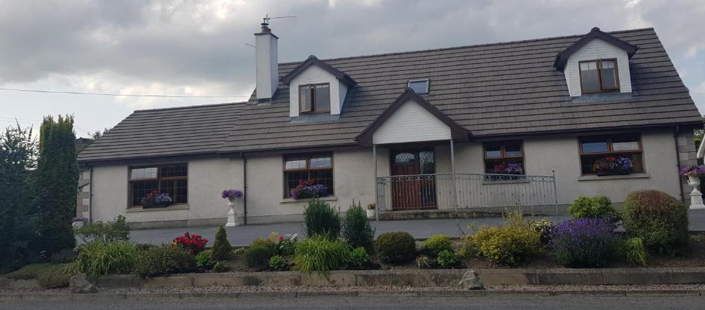 una casa blanca con flores delante en The Madden Guest House, en Gilford