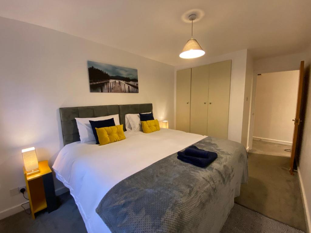 1 dormitorio con 1 cama blanca grande con almohadas amarillas en Marie’s Serviced Apartment 2 bed Olivier Court, en Bedford