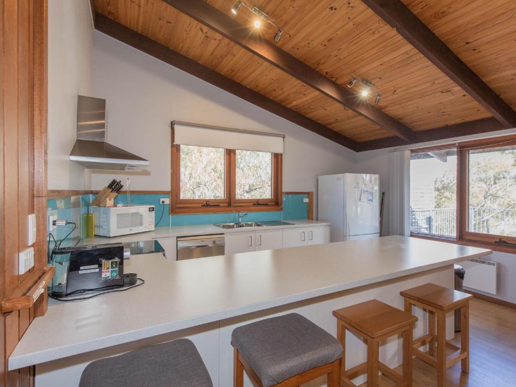 a kitchen with a large white counter top and wooden ceilings at The Lakefront 69 Townsend Street in Jindabyne