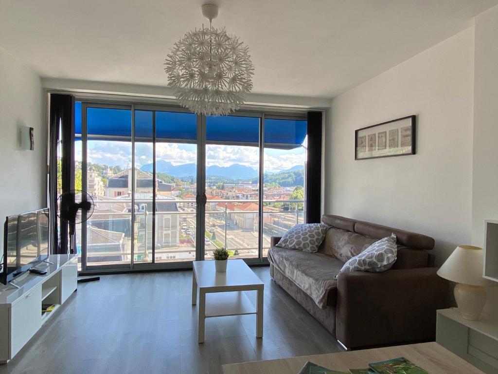 een woonkamer met een bank en een kroonluchter bij Studio moderne et lumineux centre ville Aix les Bains in Aix-les-Bains