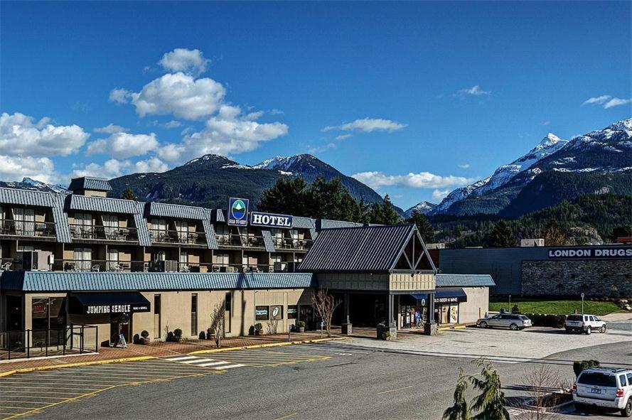 a hotel with a parking lot in front of a mountain at Sea to Sky Hotel and Conference Centre in Squamish