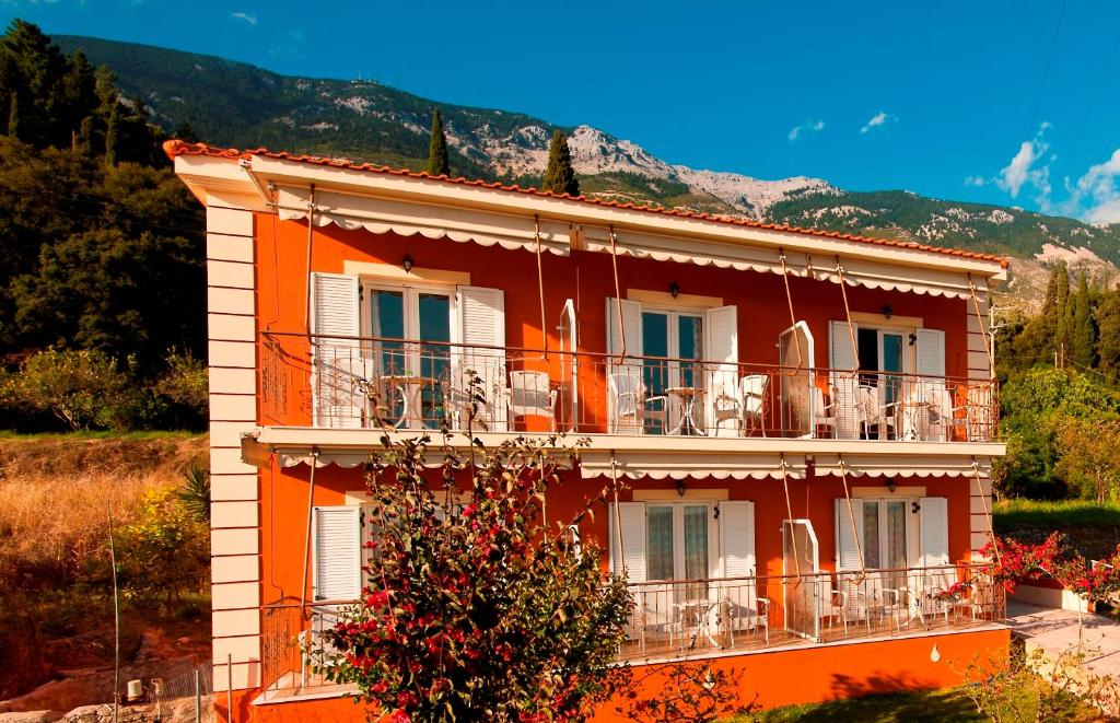 an orange building with a balcony and mountains in the background at Diona Studios in Lourdata