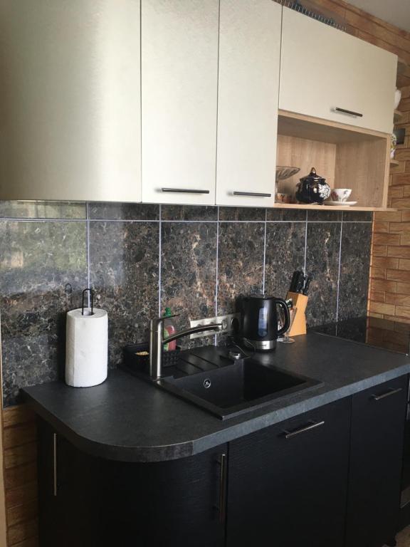 eine Küche mit einem Waschbecken und einer schwarzen Arbeitsplatte in der Unterkunft Rātes Vārti Apartamenti in Madona