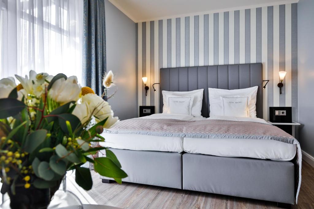 a bedroom with a white bed with a striped wall at Sylthotel Raffelhüschen Garni in Westerland (Sylt)