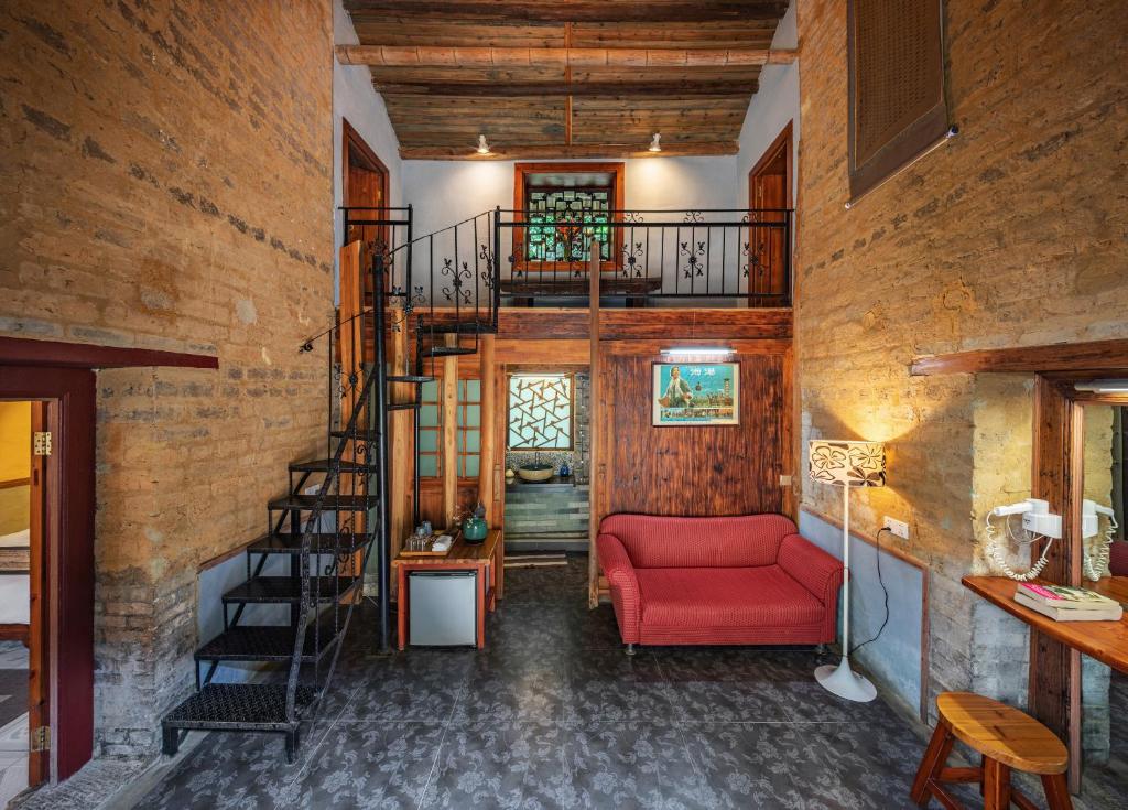 a living room with a red couch and a spiral staircase at Yangshuo Secret Garden in Yangshuo