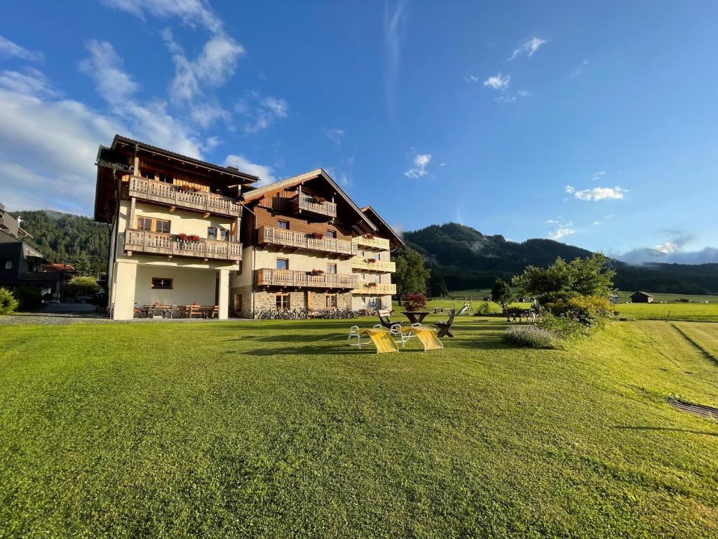 ein großes Gebäude mit einem großen Grasfeld davor in der Unterkunft Haus Heimat in Weissensee