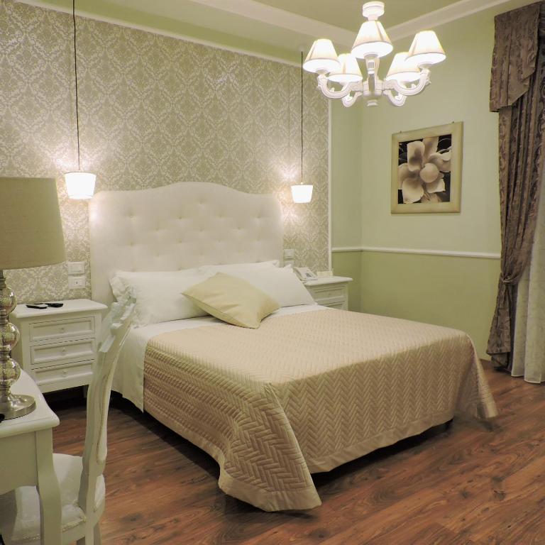 a bedroom with a white bed and a chandelier at Boutique Hotel Masolino in Panicale