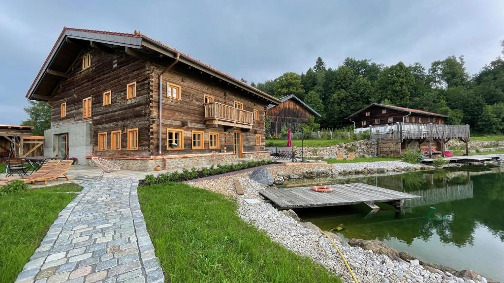 una cabaña de madera junto a un lago con un puente en Ferienhaus rehberg14, en Drachselsried