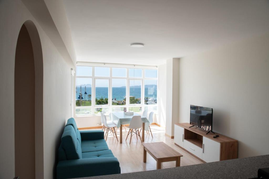 sala de estar con sofá azul y mesa en Primera Linea de Playa Samil Costa con Garaje Incluido, en Vigo