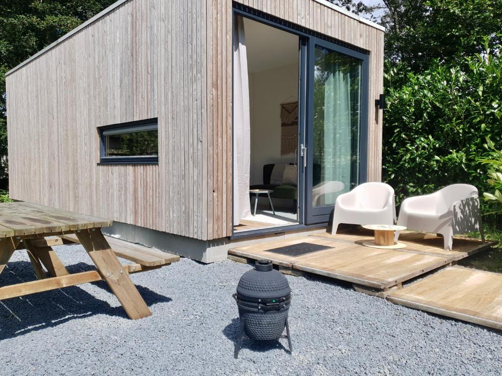 una pequeña casa de madera con mesa de picnic y sillas en Modern Tiny House op rustig Watersportpark en Elahuizen