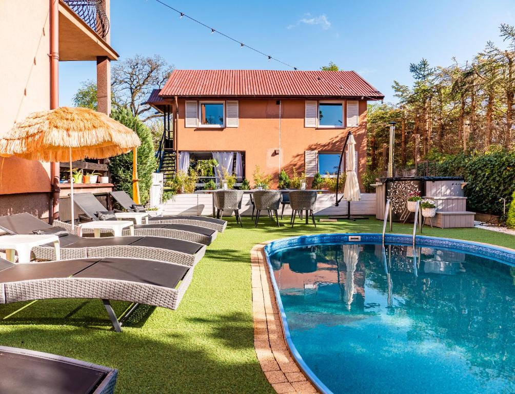 a backyard with a pool and chairs and a house at Domek InoSasino z basenem i sauną in Sasino