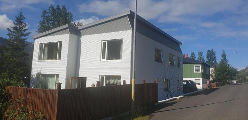 una casa blanca con una valla delante en Apartment Tungata, en Seyðisfjörður