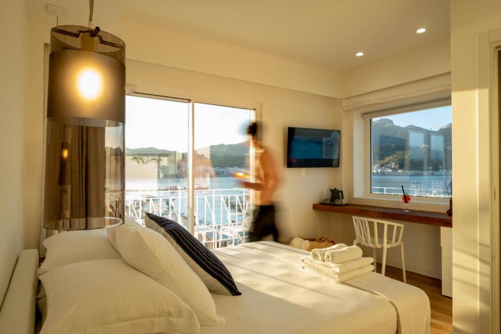 a bedroom with a white bed and a large window at La Sirena Rooms in Giardini Naxos