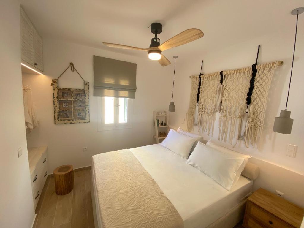 a bedroom with a white bed and a ceiling fan at Corfu, Glyfada, Sea la vie apartment in Glyfada