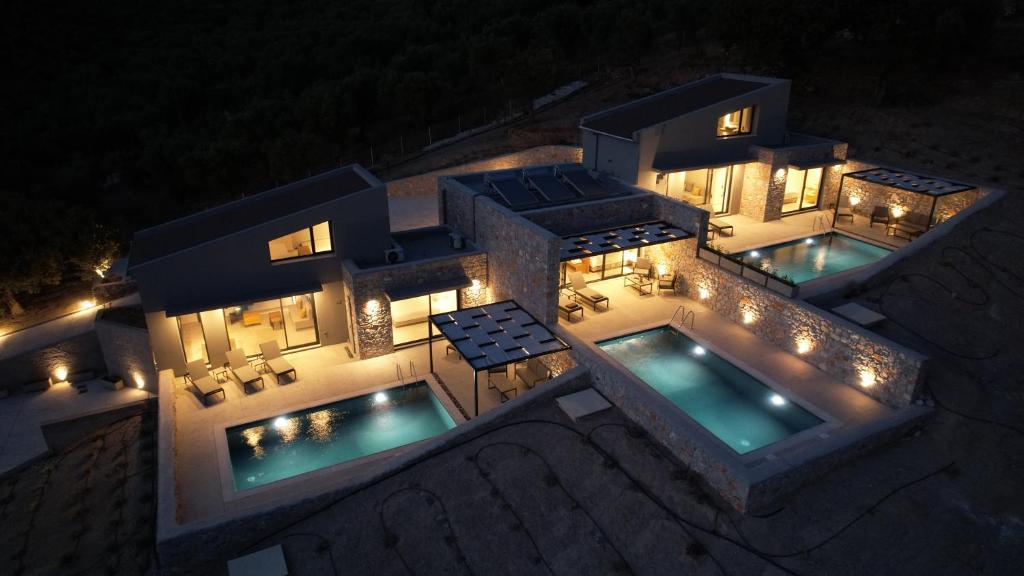 an aerial view of a house with two pools at night at DAELIA Villas in Plomari