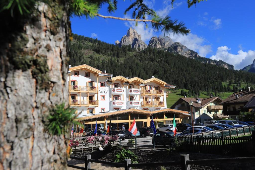 a large hotel with a mountain in the background at Hotel Chalet Alaska in Pozza di Fassa