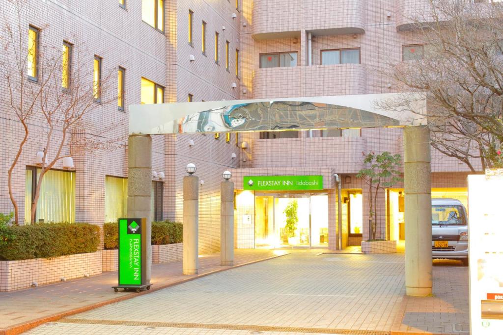 un edificio con una señal verde delante de él en FLEXSTAY INN Iidabashi en Tokio