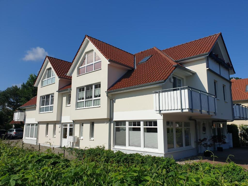 a white house with a red roof at Möwenblick Nr 3 - für die schönste Zeit des Jahres - all inclusive - Wäschepaket - PowerWLAN - eigene Fahrradbox mit Stromanschluß und kostenfreier Parkplatz in Zingst