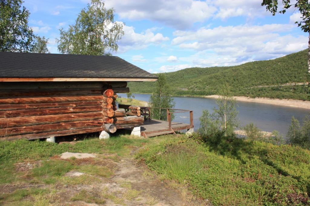 uma cabana de madeira com uma ponte ao lado de um rio em Tenon näköalamökit em Utsjoki